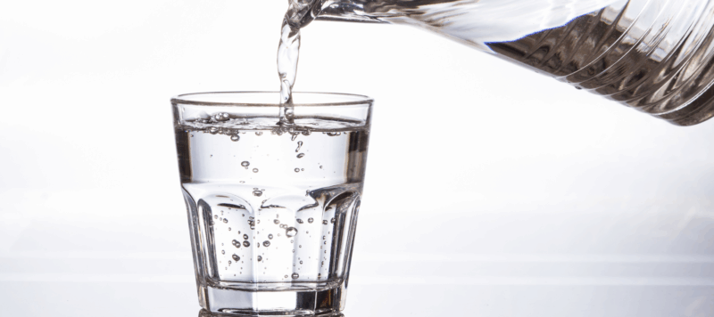 Clean drinking water being poured into a glass after whole home water filter installation in Dallas